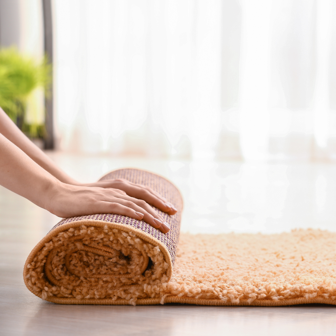 A person rolling up a rug