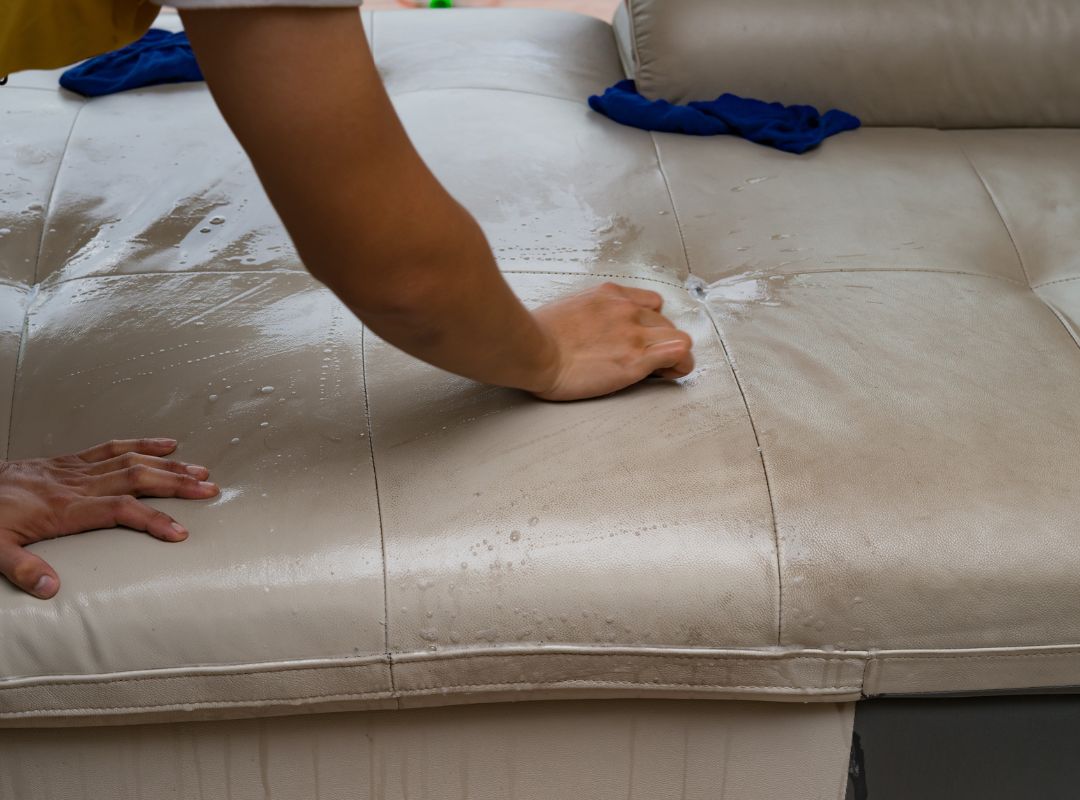 2 Expert Conditioning and Restoration a person cleaning a very dirt leather couch