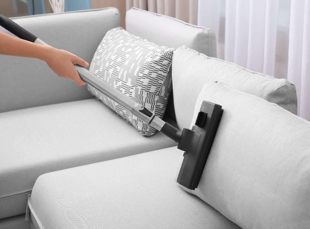 a person vacuuming couch pillows