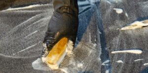 gloved hand scrubbing a black carpet